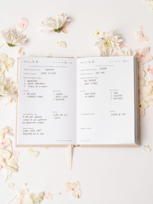 Lavendaire Daily Planner opened with pages filled in surrounded by flower petals
